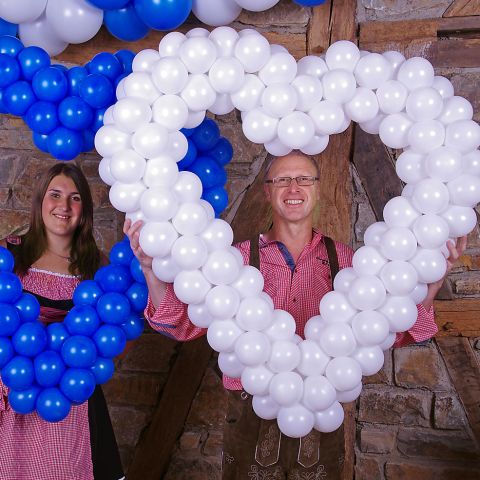Easy-Fix-Herz aus Luftballons. Auf easy-Fix-Gestänge aufgezogene Ballons in weiß mit Personen im Hintergrund