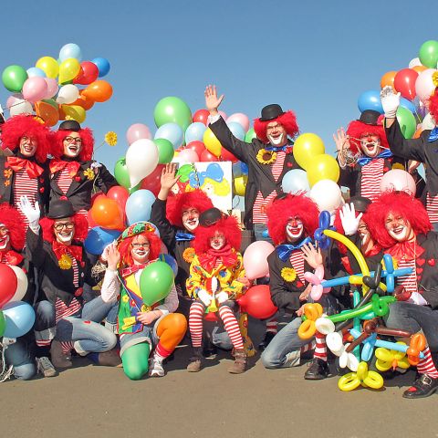 Bunte Clowngruppe mit vielen Luftballons.
